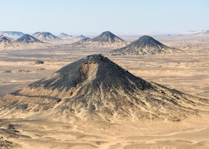 The distinctive black volcanic hills and iron-rich sand of the Black Desert in Egypt