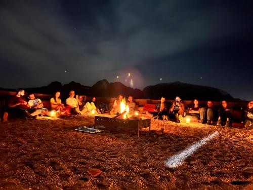 enjoying a Bedouin BBQ dinner around a campfire, with the warm glow of the fire illuminating faces and food in the desert night
