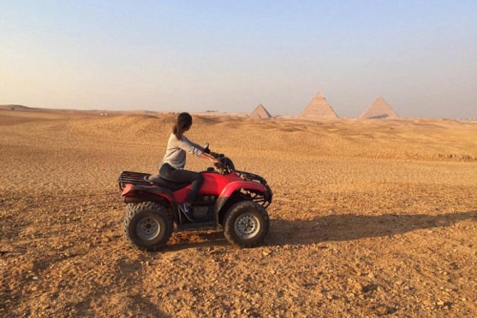 Un quad tout-terrain roulant dans le désert près des pyramides de Gizeh, avec des touristes explorant le site
