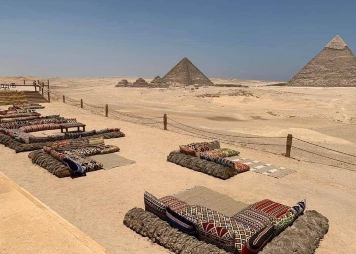 Un dîner bédouin traditionnel avec un feu de camp, des tapis et des convives, des pyramides de Gizeh en arrière-plan