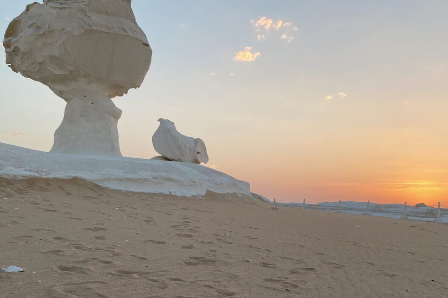Plusieurs roches champignons blanches se dressant dans le Désert Blanc sous un coucher de soleil