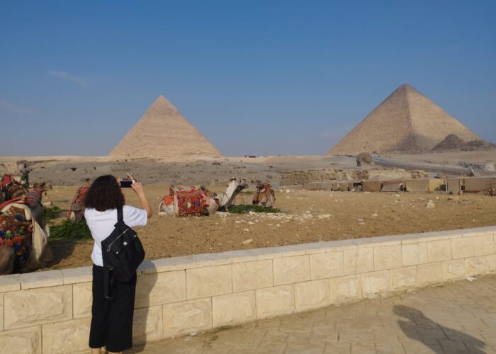 Un touriste debout devant les majestueuses pyramides de Gizeh en Égypte