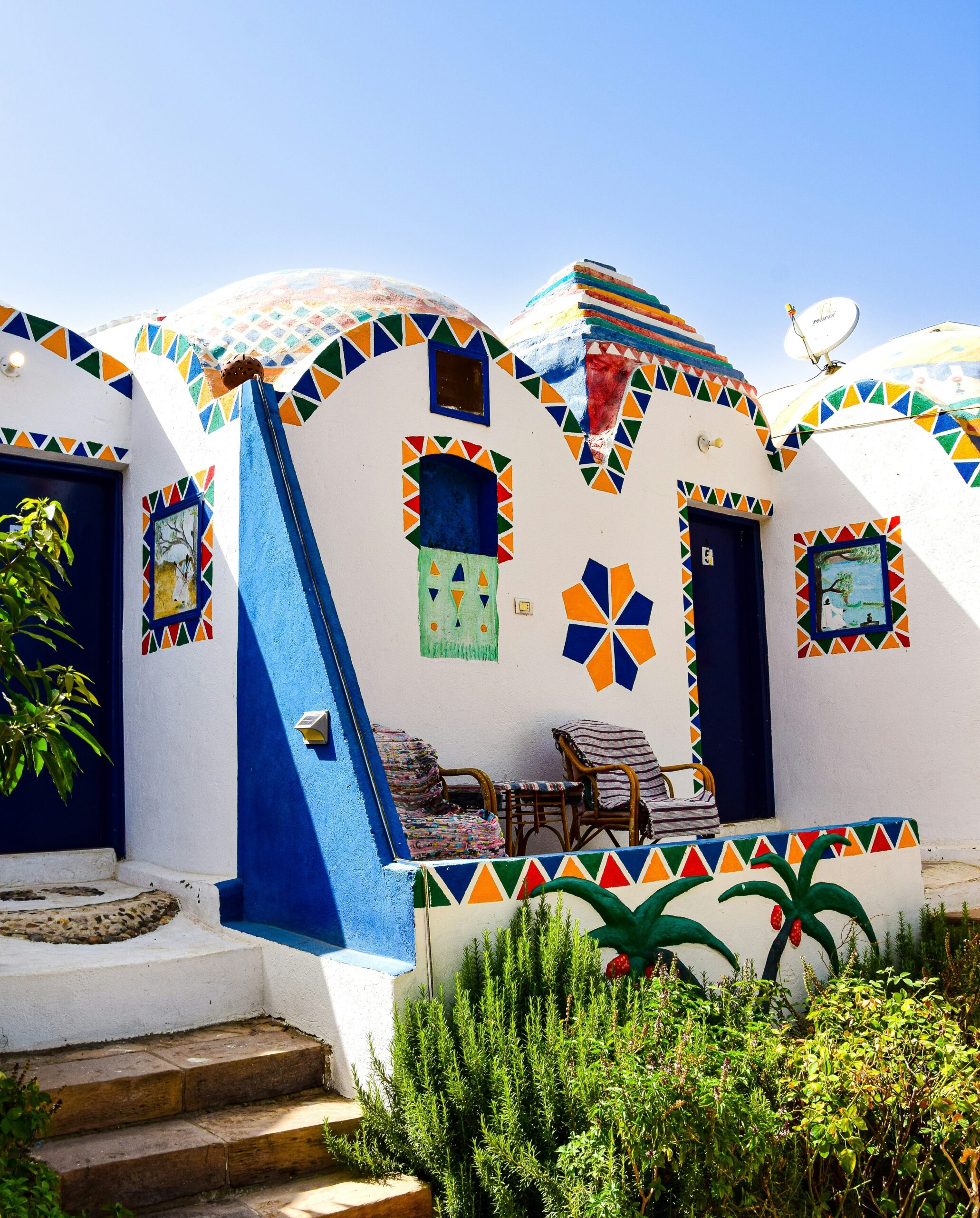 A peaceful Nubian Village nestled by the serene waters of the Nile River in Aswan, with traditional felucca boats nearby