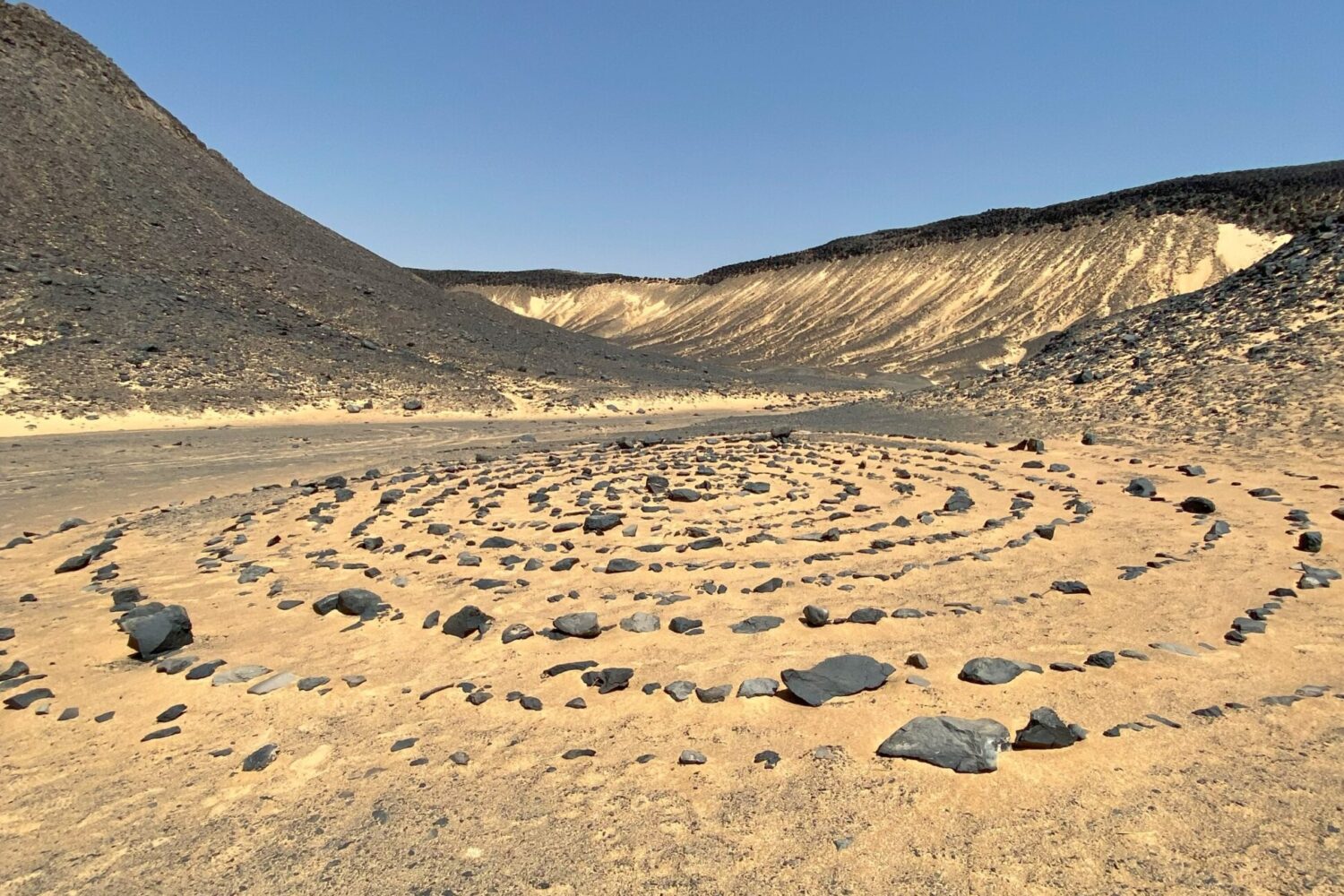 Colline e formazioni rocciose scure e coniche, coperte di pietre vulcaniche nere, che si estendono nel Deserto Nero d'Egitto