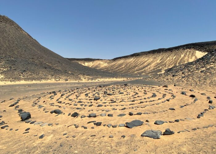 Des collines et formations rocheuses sombres et coniques, recouvertes de pierres volcaniques noires, s'étendant dans le Désert Noir en Égypte