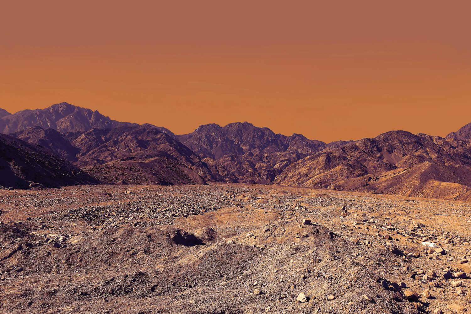 Paesaggio desertico del Sinai con forti contrasti di colore tra la sabbia ocra, le rocce scure e le sfumature blu del cielo