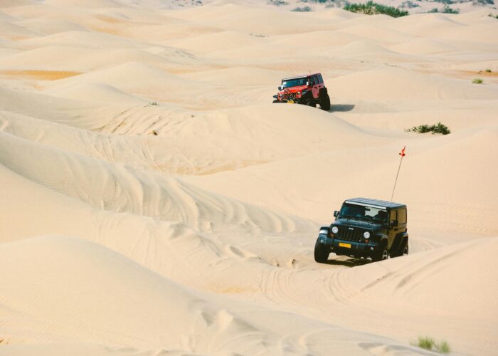 Un 4x4 robuste naviguant sur des dunes de sable, levant de la poussière lors d'un safari dans le désert en Égypte