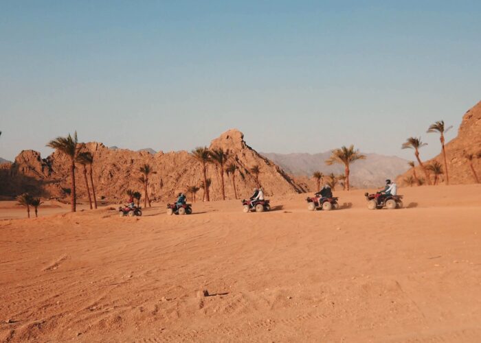 A group of people on quad bikes navigating a desert trail near Hurghada